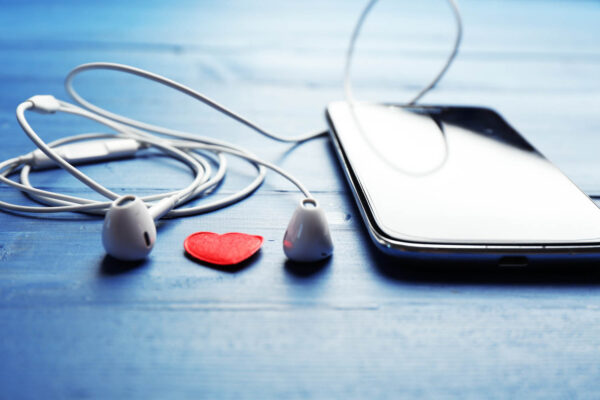 Mobile phone and earphones on color wooden background